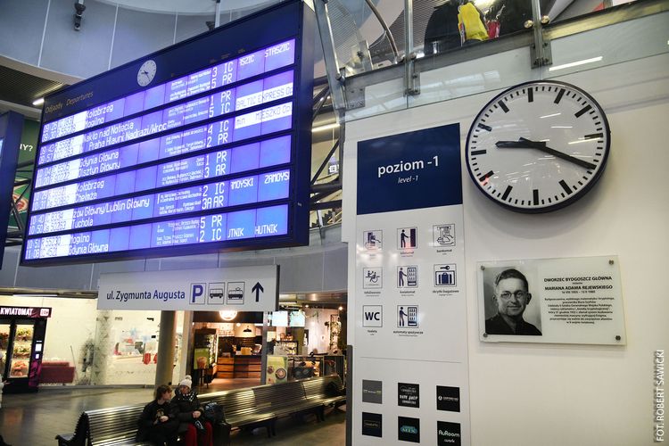 W hali dworca kolejowego zbliżenie na tablicę pamiątkową z wizerunkiem Mariana Rejewskiego.