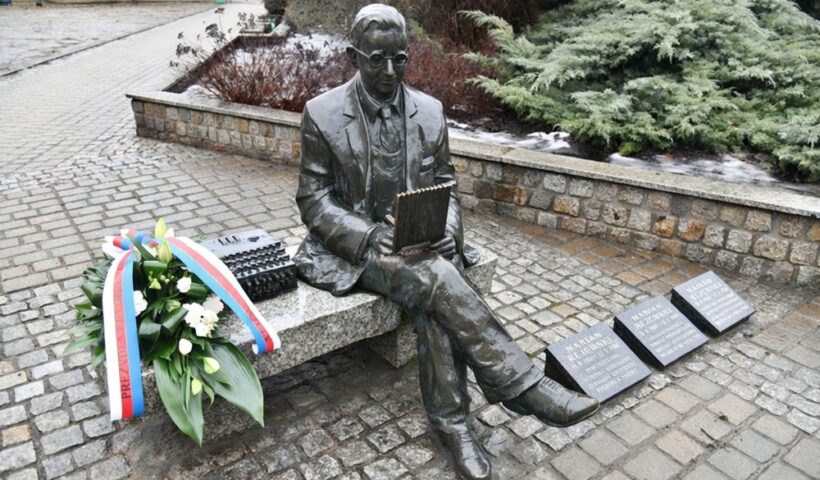 Pomnik Mariana Rejewskiego w formie ławeczki, na której sieci postać. Obok wieniec z szarfami.