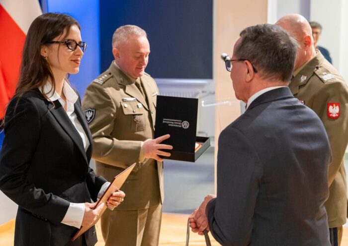Dwóch oficerów i dwoje cywilów w trakcie wręczania nagrody.